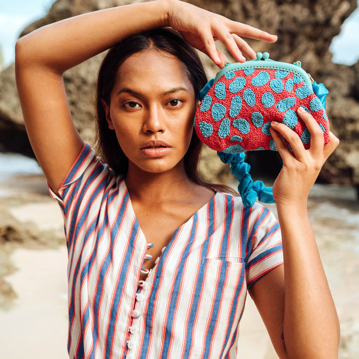 BrunnaCo Arnoldi Ariela Handbeaded clutch in red and turquoise blue color is an artisanal handmade piece by female artisans in Bali. This handbag clutch is carefully and sustainably made using glass beads in playful polka dot pattern.