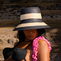 Nona Stripes Bucket Straw Hat. Meet NONA, the stylish and versatile bucket hat that is perfect for a day at the beach, a walk in the park, or a casual summer brunch. Nona - which means “Miss” in Bahasa Indonesia - is handwoven from Balinese natural palm leaves, its natural straw construction is lightweight and breathable, while the brim provides ample sun protection. The striped design adds a touch of personality, while the simple, classic shape ensures that this hat will never go out of style.