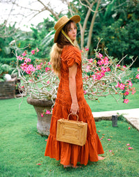 Inka Williams is holding BrunnaCo's Rahayu Atta Rattan Bag handmade in Bali using natural Atta rattan straws from Lombok. Inka is wearing BrunnaCo's Srikandi Ruffle Christmas dress in Sienna Brown. Designed in California.