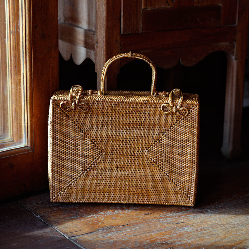 Inka Williams is holding BrunnaCo's Rahayu Atta Rattan Bag handmade in Bali using natural Atta rattan straws from Lombok. Inka is wearing BrunnaCo's Srikandi Ruffle Christmas dress in Sienna Brown. Designed in California.