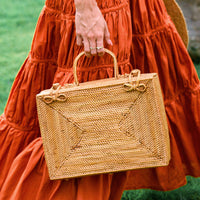 Inka Williams is holding BrunnaCo's Rahayu Atta Rattan Bag handmade in Bali using natural Atta rattan straws from Lombok. Designed in California.