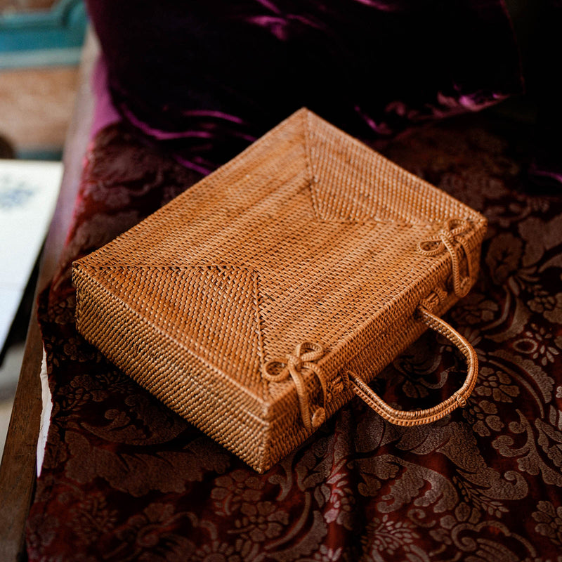 Inka Williams is holding BrunnaCo's Rahayu Atta Rattan Bag handmade in Bali using natural Atta rattan straws from Lombok. Inka is wearing BrunnaCo's Srikandi Ruffle Christmas dress in Sienna Brown. Designed in California.