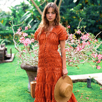 Inka Williams is wearing BrunnaCo's Sienna Brown Srikandi Ruffle Cocktail Dress in a beautiful day in Canggu, Bali, holding a straw hat