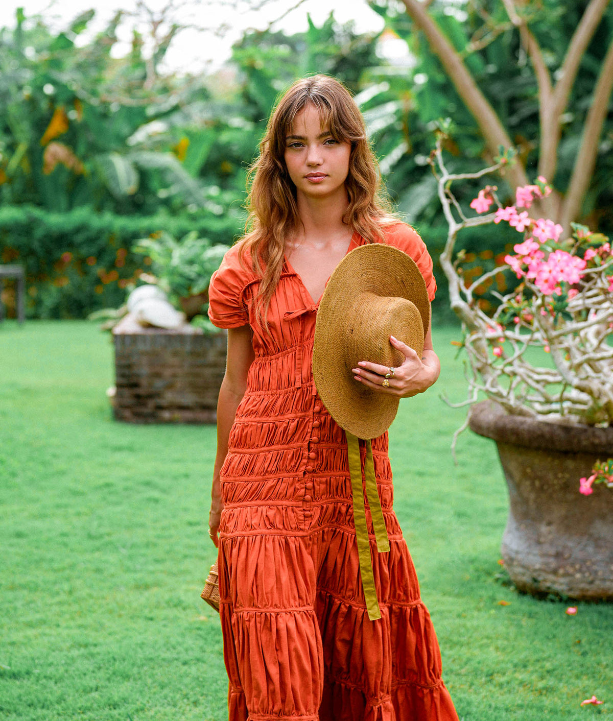 Inka Williams is wearing BrunnaCo's Sienna Brown Srikandi Ruffle Cocktail Dress in a beautiful day in Canggu, Bali, holding a straw hat. This shot is beautifully taken by Faruq Adib from Matarasa Indonesia