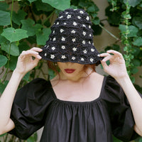 Flora Crochet Hat in Black. This gorgeous crochet hat made from 100% cotton yarn, complete with an eye-catching flower pattern, is designed to give you a fun and feminine fit.  A must-have collection for creating a cute and casual look. Hand-crocheted with love by our female artisans from their very own home in Bali.