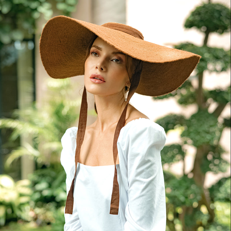 Lola Wide Brim Jute Straw Hat In Havana Brown. Braided meticulously by artisans in Gianyar, Bali from natural Jute material, this sweet hat offers both comfort and elegance. Designed with ideal thickness and weight that allow its brim to be easily folded, stretched, and styled, making it easy to take to any holiday trips or summer vacation.