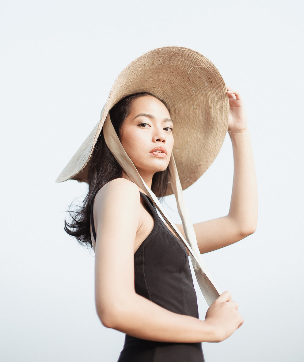 Lola Wide Brim Jute Straw Hat In Natural Beige. This sun hat is hand-weaved meticulously by women artisans in Gianyar, Bali from natural Jute material, this sweet hat offers both comfort and elegance. Designed with ideal thickness and weight that allow its brim to be easily folded, stretched, and styled, making it easy to take to any holiday trip. 