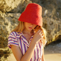 Naomi Jute Bucket Hat in red is designed specifically for the wild at heart with classic sophistication. Enjoy lounging poolside or exploring the city on sun-soaked days as its protective hat brim provides ample shade. Made of natural jute straws which have the perfect weight, this hat will sit comfortably and won't fly away in sudden gusts. It's also very practical to pack in any size luggages and ideal to take on any trips.