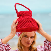 Petite Naga Macrame Crochet Bucket Beach Bag in Red. This bucket bag is made with hand-dyed macrame cotton ropes by our female artisan community in Java, Indonesia. It takes at least around 80 hours to make each bag, and this project helps to provide jobs and security for the artisans in this region.