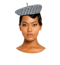 A woman is wearing BrunnaCo Simone Beret hat and she's ready for a casual stroll at the beach. The parisian beret hat has gingham pattern in black and white color